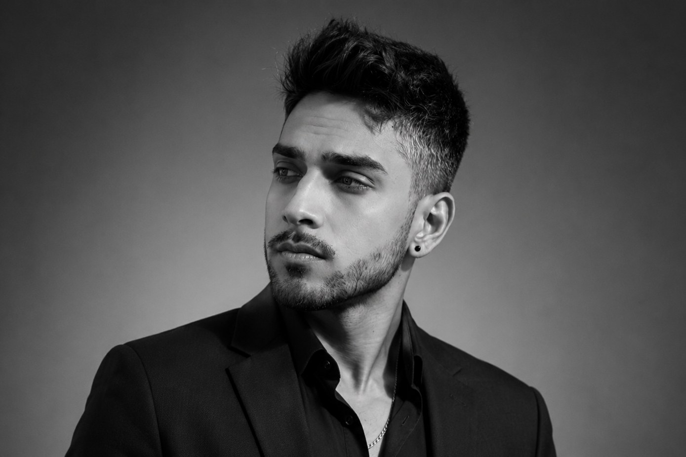Black and white studio portrait of Norwyn K, looking off camera.